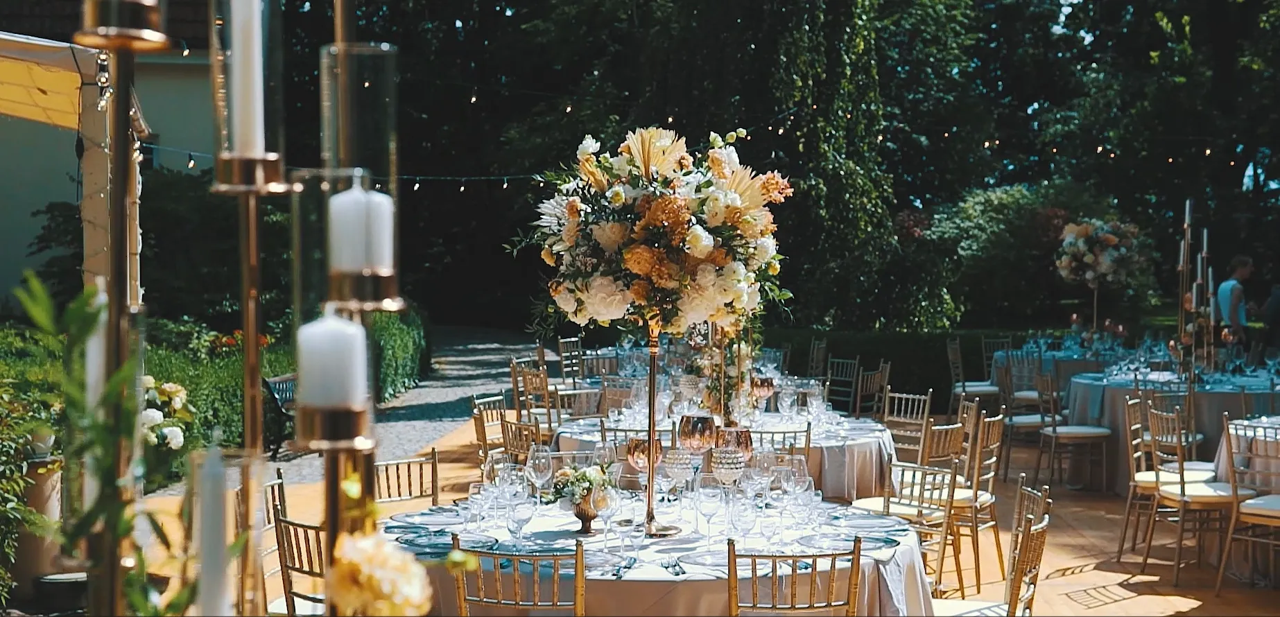 Banquet tables with tall floral centrepieces in the garden